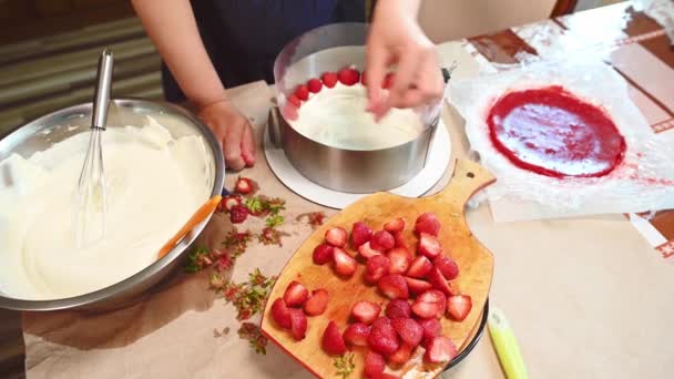 ムースケーキ 甘い夏のフランスのデザートの上に新鮮な有機イチゴの半分を置く主婦のクローズアップビューフライザー ビスケット ムース ゼリーのイチゴケーキ — ストック動画