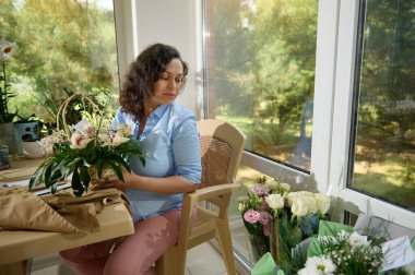 Afro-Amerikan güzel kadın, yaratıcı çiçekçi çiçekçi çiçekçi çiçek tasarım stüdyosunda egzotik orkide çiçekleri olan güzel bir buket yapar. Çiçek dükkanı ve teslimat servisi. Küçük bir iş. Düzenleme ve hediyeler