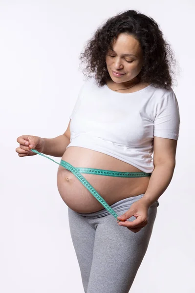 多种族的肥胖妇女用白色背景的胶带测量她的胃 怀孕的腹部测量 婴儿健康监测概念 怀孕了母性 妇女的健康和身体护理 — 图库照片