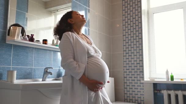 Afrikai Amerikai Felnőtt Terhes Fehér Fürdőköpenyben Áll Otthoni Fürdőszobában Mosolyog — Stock videók