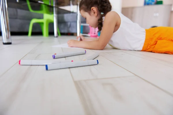 床に横たわって絵を描く4歳の白人の創造的な小さな子供の女の子の背景にフェルト先端のペン 水彩マーカー アート 絵画だ 創造的な趣味 ライフスタイル — ストック写真