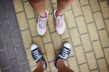 Pembe ve mavi spor ayakkabılı, kaldırımda duran erkek ve kadın bacaklarına bakın. Seçici odaklanma. Yakın plan. Reklam alanını kopyala