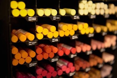 Bir okul kırtasiye dükkanının sanat bölümünde rafta sergilenen pastel renkler çizmek için sıcak renk spektrumlu parlak renkli kalemler üzerine seçici bir odak. Sanat ve hobi. Durgun hayat.