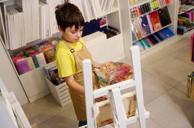 Latin asıllı, çekici bir gencin tuval üzerinde resim yapmaktan zevk aldığını, ahşap sehpada durduğunu, resim atölyesinde fırça ve palet tuttuğunu gördüm. Çocuklar işte. Eğitim. Güzel sanatlar. Yaratıcı hobi