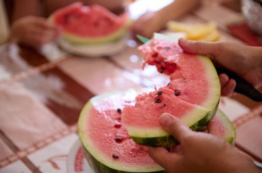 Yakından çekilen eller olgun organik sulu bir karpuz dilimini tutuyor. Yiyecek ve içecek konsepti. Çiğ vejetaryen diyeti