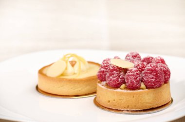 Fransız tatlısıyla güzel bir hayat kompozisyonu. Beyaz tabakta ahududu ve limonlu tart.