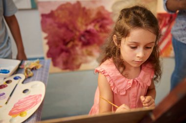 Yetenekli ilkokul çocuğu, yaratıcı hobisinin tadını çıkaran yaratıcı ressam kız çocuğu, sıcacık sanat atölyesinde suluboya resim yapan, yaratıcı beceri ve hayal gücünü geliştiren. Görsel sanat