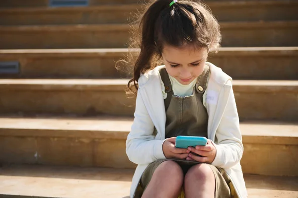 Mobile phone and internet addiction. Child girl using smartphone outdoors.