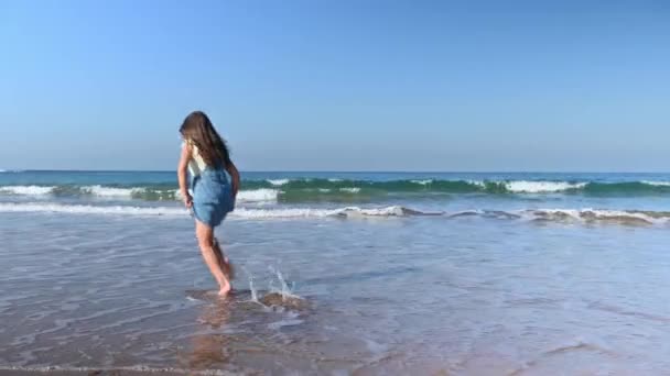 一个快乐的小女孩赤脚在热带海滩上玩耍 享受着海水在她的脚上飞溅 留下的脚印被海浪冲刷在沙滩上的全长肖像 — 图库视频影像