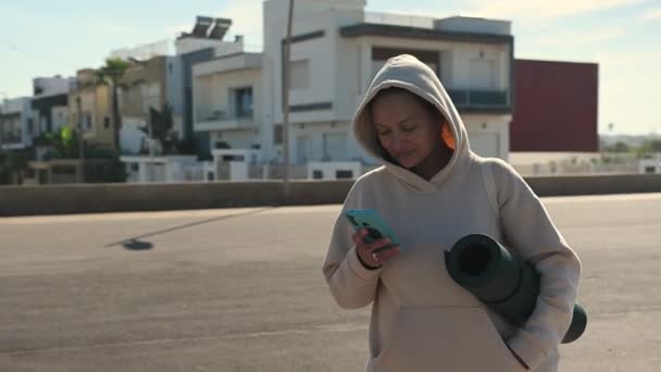 Młoda Wysportowana Kobieta Beżowej Bluzie Sprawdzająca Aplikację Mobilną Swoim Smartfonie — Wideo stockowe