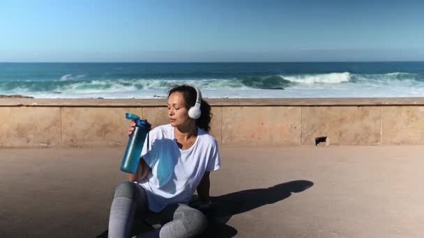 Gelukkige Atletische Vrouw Hoofdtelefoon Drinken Van Water Uit Een Fles — Stockvideo