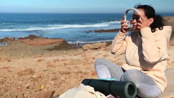 Multiethnische Frau Mittleren Alters Sportbekleidung Auf Der Steinbrüstung Vor Meeresgrund — Stockvideo