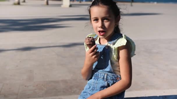 Όμορφο Κοριτσάκι Denim Sundress Τρώει Νόστιμο Παγωτό Κορνέτα Σοκολάτας Κάθεται — Αρχείο Βίντεο