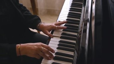 Müzik okulunda piyano çalan bir piyanistin elleri ağır çekimde. Müzisyen parmaklarını piyano tuşlarına yakın çekerken yetenekli müzisyen bir melodi ya da müzikal kompozisyon icra ediyor.