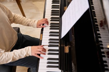 Piyano çalarken parmaklarını piyano tuşlarına koyan tanınmayan müzisyenlerin kapalı alanda klasik müziğin performansının keyfini çıkarın. Çocukların eğitimi ve eğlencesi. Boşluğu kopyala