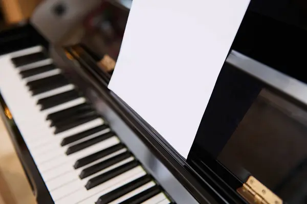 Close-up shot of classical piano and white paper sheet with music notes for performing musical composition. Learning music and playing on classic luxury vintage chord musical instrument. Copy ad space