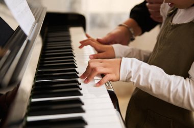 Piyano klavyesinde çocuk elinin yan görüntüsü, piyanoda müzik çalarken beyaz ve siyah tuşlara dokunmak. Akort aleti. Müzik dersi. Sanat eserleri. Kültür. Hobiler ve eğlence