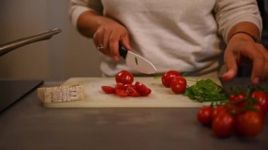Yakın plan. Mutfak bıçağı kullanan, taze organik domatesleri doğrayan ev mutfağında sağlıklı vejetaryen salatası hazırlayan bir kadının ellerinde. - İnsanlar. Yiyecekler. Yaşam Tarzları