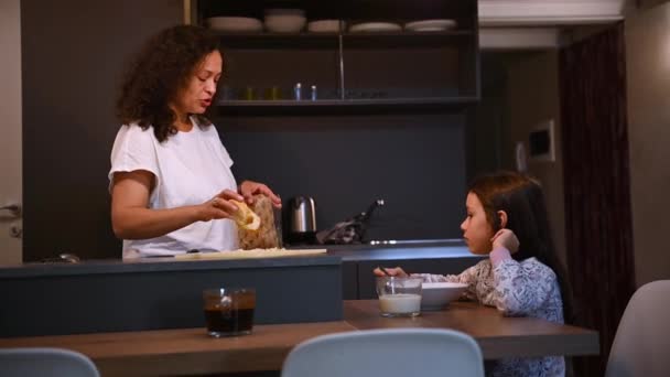 一个可爱的小女孩的生活方式肖像 可爱的女儿在家里厨房吃早餐的时候和妈妈说话 大家好早上例行公事家庭关系 — 图库视频影像