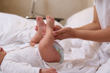Tanımlanamayan bir kadının elleri bebek bacakları tutuyor ve düztaban ve ortopedik hastalıklar için nazik masaj hareketleri yapıyor. Pediyatri. Sağlık ve İlaç Hizmetleri