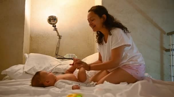 妈妈在新生儿身上换尿布 妈妈在婴儿身上换尿布躺在舒适的卧室里的床上 婴儿期 婴儿保育和卫生概念 产妇生活方式 — 图库视频影像