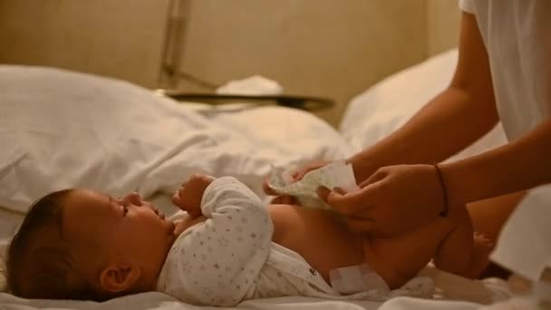 在妈妈给他换尿布的时候 可爱的婴儿躺在床上的特写 幼儿保育和幼儿概念 育儿假和产假的概念 — 图库视频影像