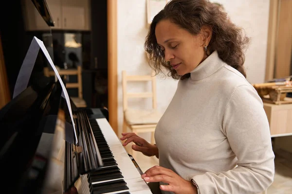 Authentic portrait of a middle aged woman performing a melody on piano forte. Musician playing grand piano. Talent. Skills, Music and people. Lifestyle