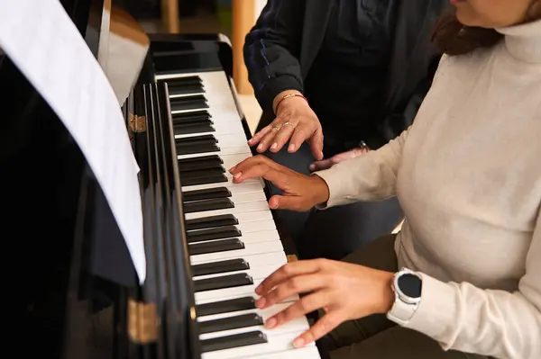 stock image Close-up view of women hands playing piano indoor during music lesson. Female pianist teacher explaining piano lesson, touching white and black piano keys, performing classical music composition