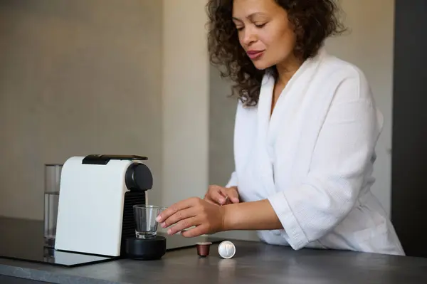 아메리카 여자는 가운에서 아침에 일어나 가정용 머신을 사용하여 신선한 에스프레소를 스톡 이미지
