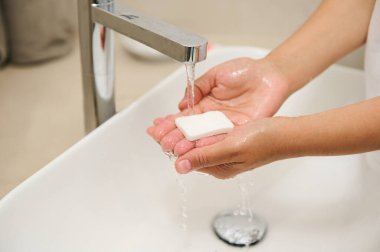 Musluk suyunun altında antibakteriyel sabunla ellerini yıkayan kadının yakın çekimi. Sağlık hizmetleri. Vücut bakımı ve hijyen kavramı. Salgın, virüs ve enfeksiyonların önlenmesi. Saflık ve hijyen kavramı