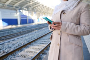 Tren istasyonunda cep telefonlarını kontrol eden kadın banliyö çalışanları. Halkın konsepti, kablosuz teknolojiler, yaşam tarzı, yüksek hızlı elektrikli treni ucuz demiryolu kentsel taşımacılığı olarak kullanmak