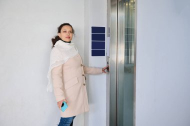 Tren istasyonunda ok asansörü düğmesine basan çok ırklı güzel bir kadın..