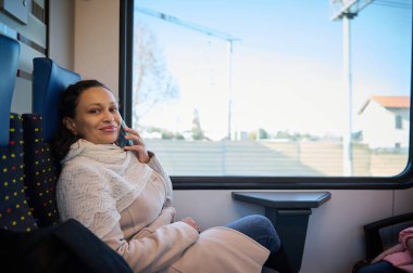 Çok ırklı, güzel bir kadın yolcu yüksek hızlı bir trenin koltuğunda oturuyor, cep telefonuyla konuşurken kameraya bakıp gülümsüyor. Şehirden şehre seyahat etmek için demiryolu ulaşımını kullanıyor.