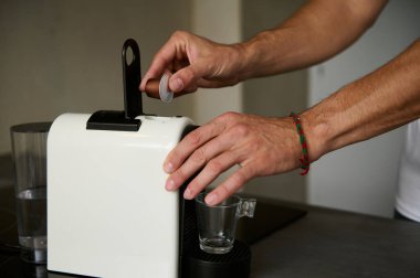 Erkek eli sabahları kahvaltı için espresso kahvesi hazırlar, öğütülmüş bir Arabika 'yı ev kullanımı için kapsül kahve makinesine yerleştirir. - İnsanlar. Boş zaman. Kahve bağımlılığı