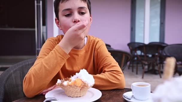 可爱的孩子 十几岁的男孩喜欢吃一份美味的冰淇淋 放在户外自助餐厅或冰淇淋店的华夫饼干盘上 大家好食品消费主义 — 图库视频影像