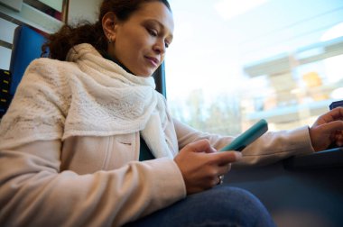 Authentic portrait of a beautiful young woman using mobile phone while travels by a high speed train. People. Online communication. Internet. Using rail road transport for cheap and comfortable trip clipart