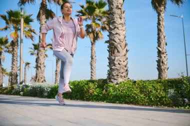 Çok ırklı orta yaşlı bir kadın koşucunun tam portresi. Sıcak bir günde koşu bandında koşuyor. - İnsanlar. Koşuyordum. Etkin sağlıklı yaşam tarzı konsepti