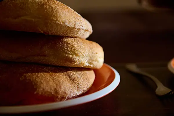 Partial view of a stack of freshly baked wholegrain bread on a ceramic plate. Close-up food photography for advertising and food blogs. Bakery. Cuisine. Culinary. Nourishment. Copy advertisement space