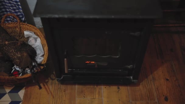 从上面的老式金属木柴燃烧炉看 里面有燃烧的原木 地板上有木柴的柳条筐 — 图库视频影像
