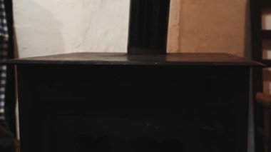 Yakın çekim erkek eli, kırsal evdeki kızgın odun sobasının üzerine sıcak bir tava koyuyor. Sıcak kırsal çevrede yemek hazırlamaya hazır. Kırsal yaşam tarzı.