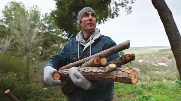 Portret Młodego Mężczyzny Ciepłych Ubraniach Stojącego Lesie Trzymającego Stos Siekanych — Wideo stockowe