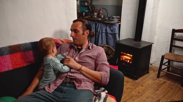 Young Dad Sits Sofa Plays His Little Baby Fireplace Backdrop — Stock Video