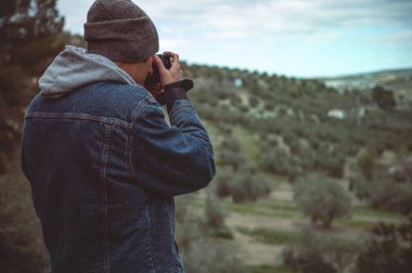 Arka manzara erkek fotoğrafçı, bahar başlarında yürüyüş ve yürüyüş yaparken, profesyonel dijital kamerasıyla dağların güzelliklerini yakalıyor. Halk ve aktif turizm kavramı