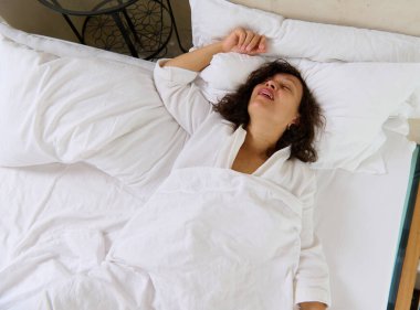 Yatağında uyurken horlayan genç bir kadının yukarıdan görünüşü. Horlama problemleri. Sağlık hizmeti kavramı