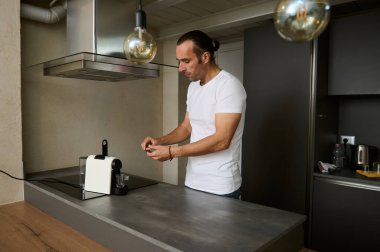 Çekici Kafkas maçosu, öğütülmüş arabika ile kapsül yerleştiriyor, ev mutfağında taze demlenmiş espresso yapıyor. İtalyan kültürü ve yaşam tarzı. - İnsanlar. Sabah rutini ve alışkanlıkları. Ev hayatı.