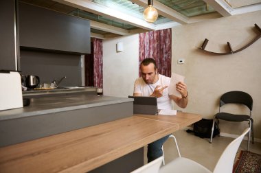 Video konferansı sırasında tartışan serbest çalışan bir erkek. İnternetteki toplantı sırasında interlokasyoncularına kağıt belgeler gösteriyor..