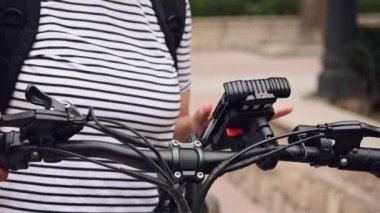 Elektrikli bisiklet kiralayan bir kadının cep telefonundaki kiralık uygulamayla görüntüsü kesilmiş. Bisikletle şehir servisini paylaşıyoruz. Elektrikli scooter 'ın kirasını ödedim. Toplu çevre taşımacılığını kiralamak ve ödemek için akıllı telefon kullanmak