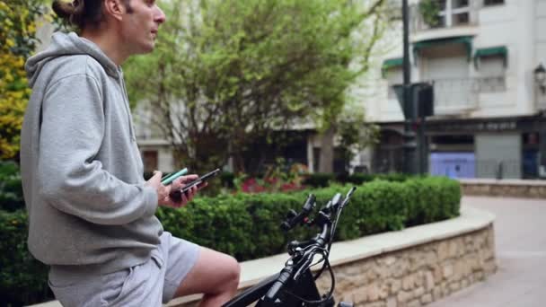 Genç Adam Şehirde Sürmeden Önce Akıllı Telefonuyla Elektrikli Bisikletinin Üzerinde — Stok video