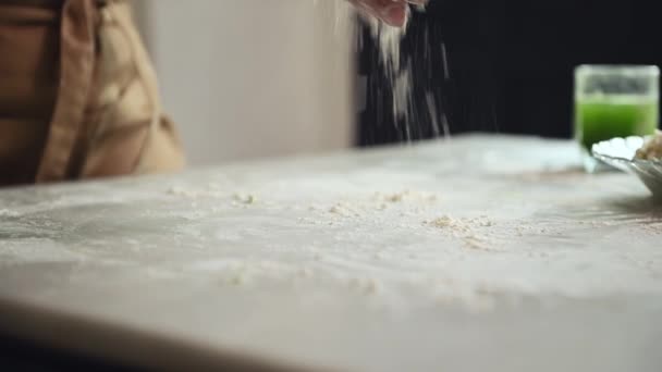 特写家庭主妇 米黄色围裙中的厨师糕点 在大理石桌上撒些白粉 在上面放上绿色菠菜的生面团 在乡村家庭厨房里准备小提琴菜 饺子或寿司 — 图库视频影像