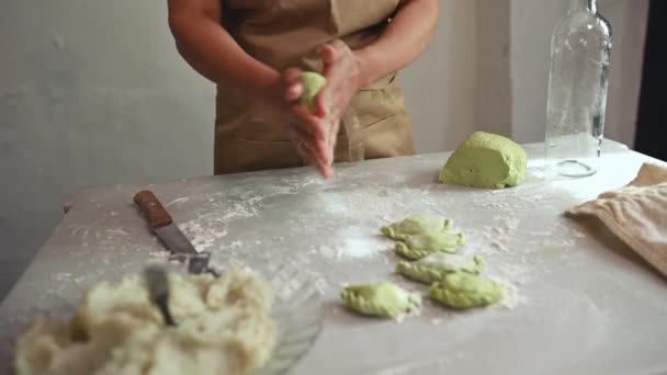 一位年轻女厨师 米黄色围裙家庭主妇 切绿色菠菜面团 做香肠和铺开面团 在农家厨房里准备饺子的具体细节 — 图库视频影像